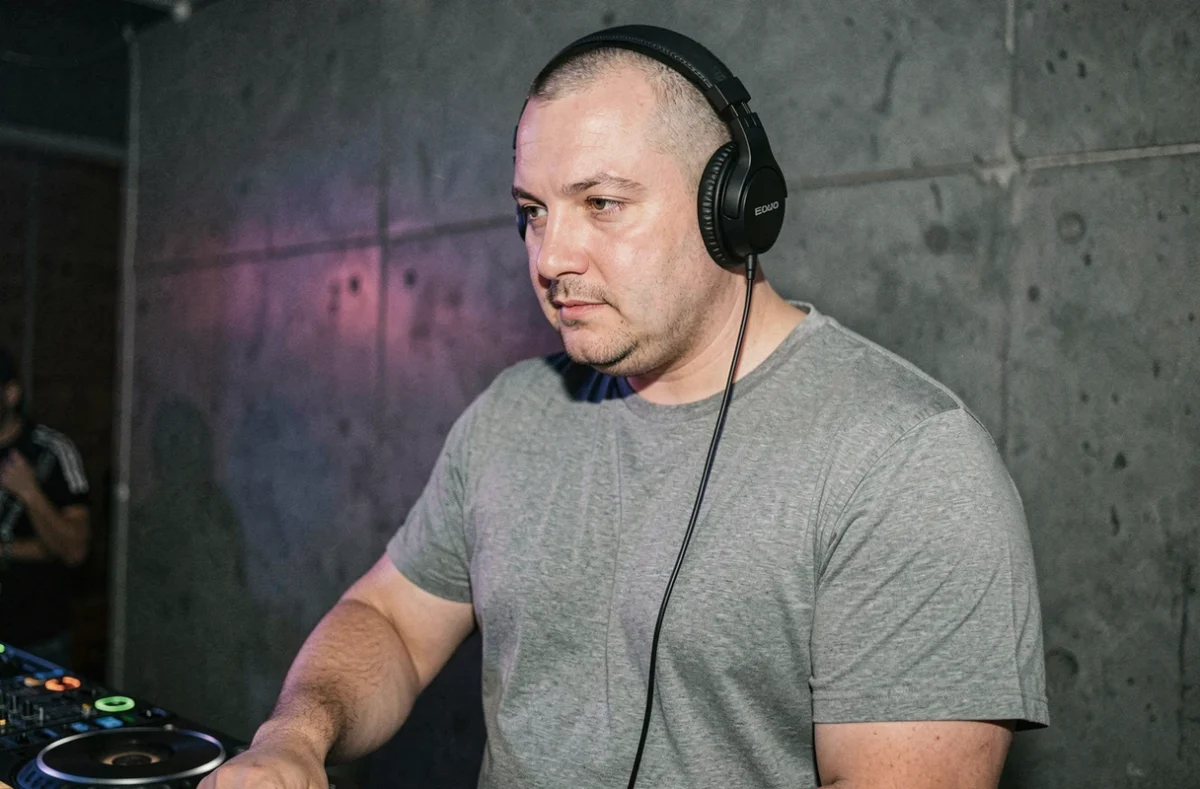 DJ Simple D, casque sur les oreilles, concentré derrière ses platines dans un club underground intimiste